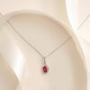 Oval stone pendant necklace with pink stone and surrounding with accents.
